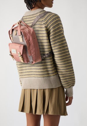 Rosa Nylontasche mit grauen Akzenten, verstellbaren Riemen und einer Fronttasche. Ein horizontal gestreifter Pullover und ein plissierter Khaki-Rock sind ebenfalls sichtbar.