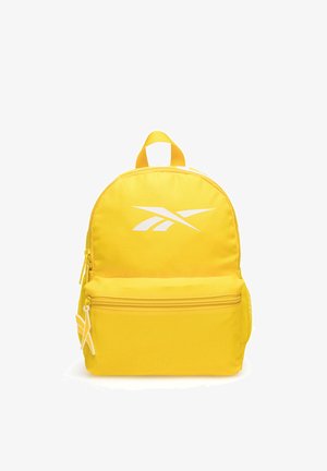 Zaino giallo con tasca frontale con zip, logo bianco sul davanti, maniglia superiore e tasca laterale in rete, fotografato su sfondo bianco.