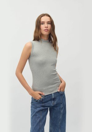 Top grigio a coste, aderente e senza maniche, con collo alto, abbinato a jeans denim blu larghi, dal design rilassato e con dettagli delle tasche in vista.