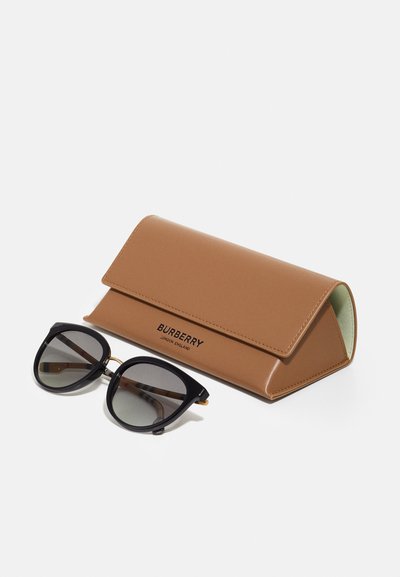 Óculos de sol pretos com lentes escuras ao lado de um estojo de couro castanho com design dobrável e marcação em relevo.
