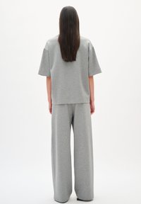Lichtgrijze gecoördineerde set met een t-shirt met korte mouwen en wijde broek, gemaakt van zachte, textuurstof. Geen zichtbare patronen of accenten.