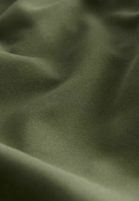 Oliiviroheline kangas, millel on sile ja matt tekstuur; pind näitab pehmeid voltimisi ja diskreetset läiget, rõhutades selle voolavust ja liikumist.