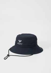 Marine blauwe bucket hat gemaakt van lichtgewicht stof met een ronde top, brede rand en verstelbare kinband. Voorzien van een witte geborduurde "ROXY" logo.