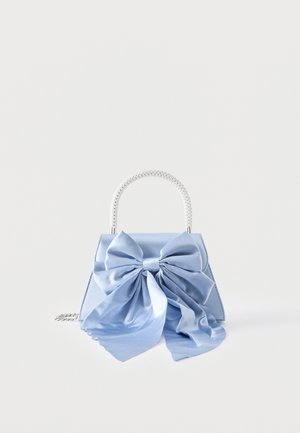 Sac à main bleu clair avec grand nœud en satin à l'avant et poignée en argent perlé sur fond blanc.