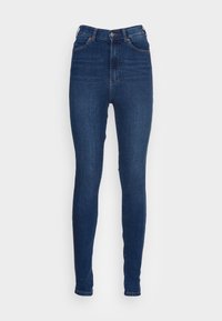 Vaqueros de cintura alta, de corte ajustado en denim azul oscuro. Cuenta con cremallera, diseño de cinco bolsillos y un ligero desgastado en la parte delantera. Textura suave.