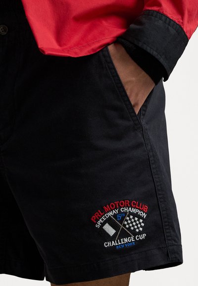 Schwarze Shorts aus Baumwolle mit gesticktem Logo, das Rennmotiven zeigt. Das Design umfasst Taschen und eine lockere Passform.
