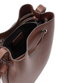 Brązowa torba typu bucket z fakturowanej skóry z zamknięciem na sznurek oraz czarną zamykaną kieszenią wewnętrzną z metką marki.