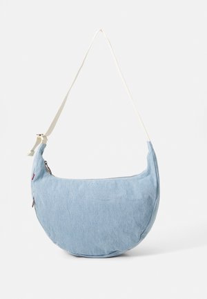 Sac bandoulière en denim bleu clair en forme de croissant avec une sangle blanche réglable et une fermeture éclair sur le dessus.