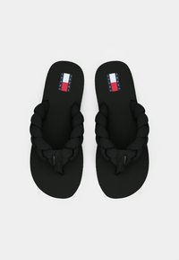 Svarta flip-flops med flätad rem, platt sula och logotyp i rött, vitt och blått på sula. Enklig design och matt yta.