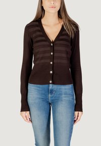 Cárdigan marrón con rayas verticales, un escote en V profundo, botonadura frontal y puños acanalados, combinado con jeans ajustados azules.