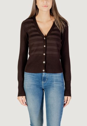 Cardigan marrone con strisce verticali, scollo a V profondo, chiusura con bottoni e polsini a coste, abbinato a jeans blu aderenti.