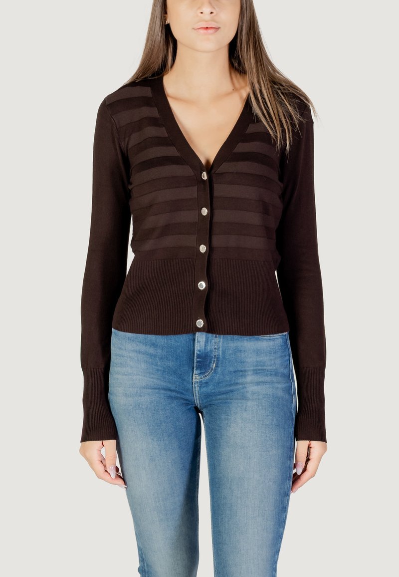 Cárdigan marrón con rayas verticales, un escote en V profundo, botonadura frontal y puños acanalados, combinado con jeans ajustados azules.