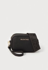 Svart texturerad läderväska med guldlogo, dragkedja och ett avtagbart band med ett kontrasterande logomönster.