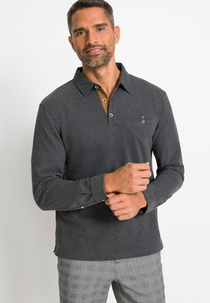Polo-shirt à manches longues gris foncé avec un col marron contrasté et un plastron à trois boutons. Doté d'une petite poche poitrine et d'une silhouette ajustée.