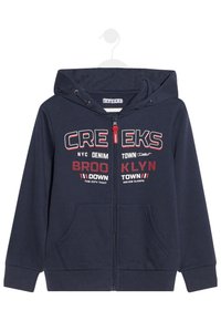 Felpa navy con zip e due tasche frontali, con testo rosso e bianco. Il materiale è morbido, con cordini regolabili sul cappuccio.