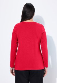 Rotes Langarmshirt aus weichem Stoff, mit Rundhalsausschnitt und lässiger Passform. Zeigt die Rückansicht mit glatter Textur und ohne sichtbare Muster.