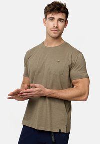 Olivengrünes T-Shirt aus weichem Stoff, mit Rundhalsausschnitt, kurzen Ärmeln und einer kleinen Brusttasche mit Knopfdetail.