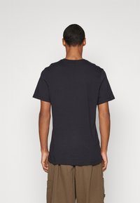 Námořnická modrá bavlněná tričko s krátkými rukávy a kulatým výstřihem, z pohledu ze zad. Jednoduchý design bez viditelných logo nebo vzorů.