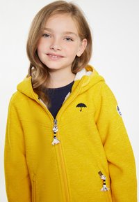 Gul zip-up huvtröja med texturerad tyg, huva och broderad paraplylogotyp. Har dekorativa dragkedjehänklar och kontrasterande innerfoder.
