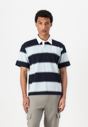 Polo skjorte med horisontale lyseblå og marineblå striper, hvit krage og brodert 'G' logo på brystet. Korte ermer, laget av bomull.