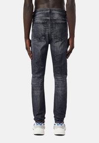 Mörkblå denimjeans med slim fit, med en klassisk fyrfickdesign och subtil blekning. Kombinerat med ljusgrå sneakers.