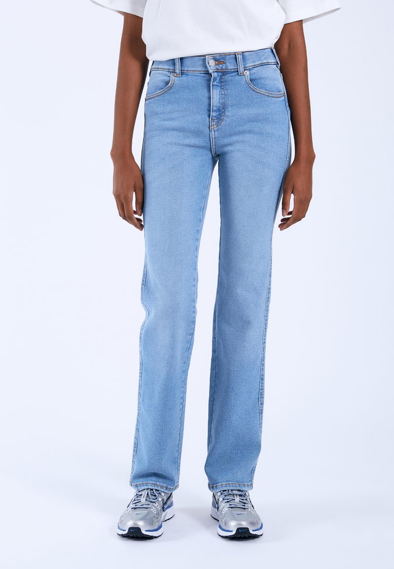 Jeans de tiro alto en azul claro con corte recto, que cuentan con bolsillos frontales, herrajes plateados y detalles de costura en contraste.