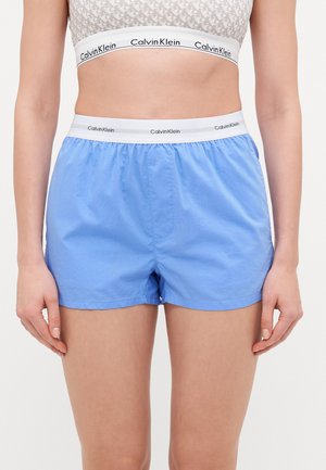 Light blue shorts made of smooth fabric, featuring an elastic waistband with a white band displaying the "Calvin Klein" logo.