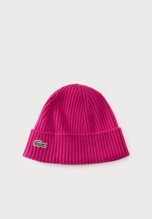 Bright pink ribbed knit beanie with folded cuff featuring a small green crocodile logo on the side, on a plain light background.