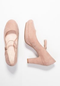 Scarpe con tacco alto in suede rosa chiaro, con punta tonda, cinturino alla caviglia e tacco spesso. Texture liscia, design minimalista.