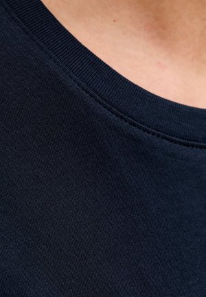 Tumesinine puuvillane kangas, sileda tekstuuriga, ümardatud kaelusega ja soonikuga krae detailidega. Õmblused on nähtavad mööda servasid.