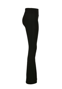 Leggings noires évasées avec une texture lisse et une taille haute, présentant un ajustement slim jusqu'à la cheville. Pas de coutures ni d'accents visibles.