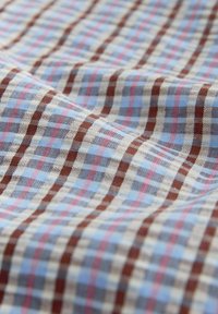 Material moale cu un model în carouri, având linii de culoare albastru deschis, maro, bej și roz care formează un design pătrat.