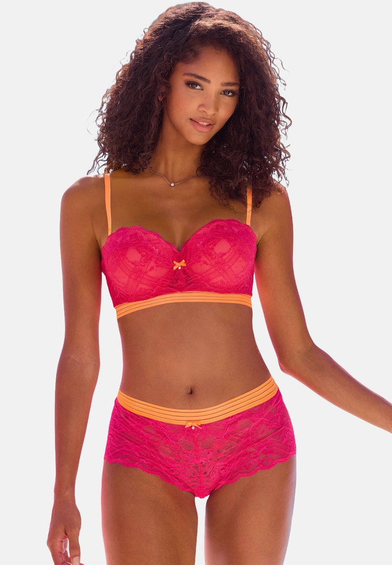 Helle rosa Spitzen-Bralette und passende Boyshorts mit orangenen Akzenten. Mit gewelltem Saum und einer Schleifendetail in der Mitte. Verstellbare Träger.