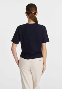 Granatowa koszulka z bawełny z krótkim rękawem, okrągłym dekoltem i luźnym krojem. Połączona z jasnymi, szerokimi spodniami.