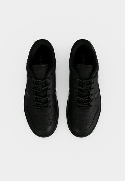 Paire de baskets noires à lacets avec orteils perforés, vues de dessus sur un fond blanc uni.