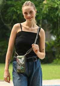 Schoudertas met bloemen- en vogelmotieven, in gedempt groen en beige, vervaardigd uit gestructureerd leer. Verstelbare schouderband, ritsluiting en een compact ontwerp.