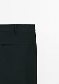 Czarne, dopasowane spodnie o gładkiej fakturze, wyposażone w szlufkę na pasek oraz pojedynczą tylną kieszeń z ukrytym zamkiem błyskawicznym.