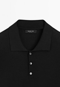 Polo noir en tissu lisse, doté d'un col côtelé, d'une patte de boutonnage à trois boutons et d'une étiquette "Massimo Dutti" à l'intérieur.