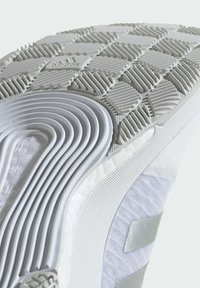 Sole di scarpa sportiva bianca con gomma texturizzata per aderenza, caratterizzata da un design a strati con coste e aree lisce. Logo del marchio argentato presente.