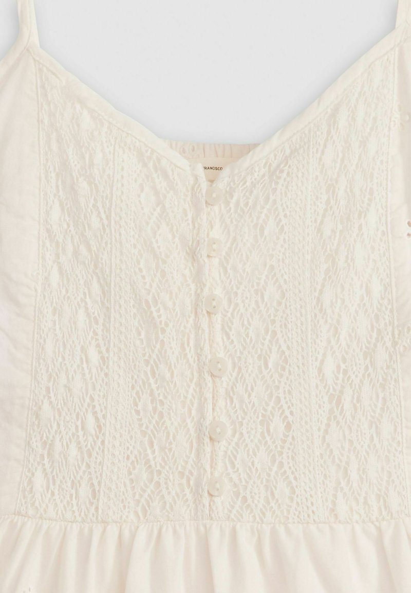 Vestido blanco con detalles de encaje en el cuerpo, escote en V y un cierre frontal con botones de tela y una falda con volantes.