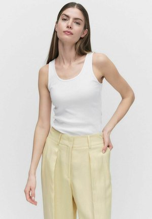 Weißes, geripptes Tanktop kombiniert mit hochtaillierten, hellgelben, maßgeschneiderten Hosen. Glatter Stoff, minimalistisches Design und klassischer Schnitt.
