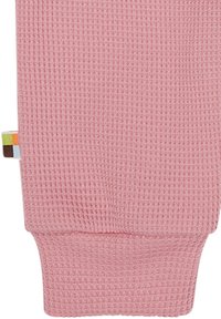 Roze wafelstructuur stof met geribbelde manchetten, met aan de zijkant een meerkleurig label met vierkante patronen in groen, geel en bruin.