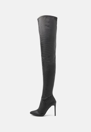 Botte noire cuissarde à talon aiguille avec bout pointu et finition en cuir texturé à motif crocodile.