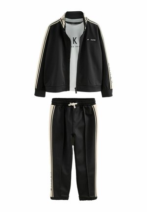 Sort atletisk træningsdragt med lynlåstrøje med hvide striber og matchende bukser med elastisk talje og manchetter. Letvægtsmateriale.