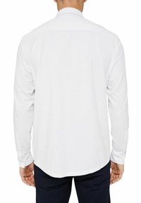White long-sleeve shirt with a collar, button cuffs, and a curved hem. Smooth fabric texture, fitted design, and no visible patterns.