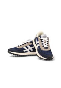 Zapatillas de running en azul marino y beige, con una parte superior de tejido texturizado, franjas blancas y una suela negra robusta para mayor tracción.