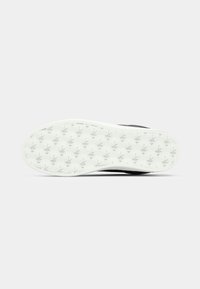 Semelle de chaussure blanche avec plusieurs petits motifs en relief de feuille de cannabis pour la traction, photographiée sur un fond clair uni.