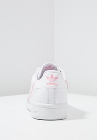 Sneaker Adidas in pelle bianca con dettagli e logo rosa sul tallone, caratterizzati da una texture liscia e da un classico profilo low-top.
