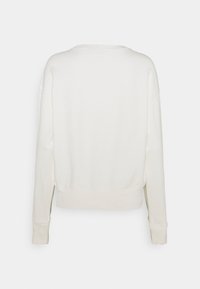 Bílé mikina s uvolněným střihem, kulatým výstřihem, dlouhými rukávy a žebrovanými manžetami. Měkká textura s postranními rozparky na lemování.