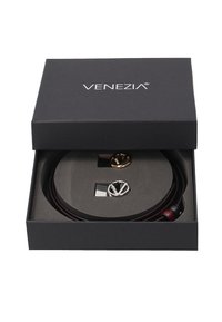 Venezia-boks med en cirkulær sort indsats, der holder to par høretelefoner med guld- og sølvaccenter i en slank sort emballage.